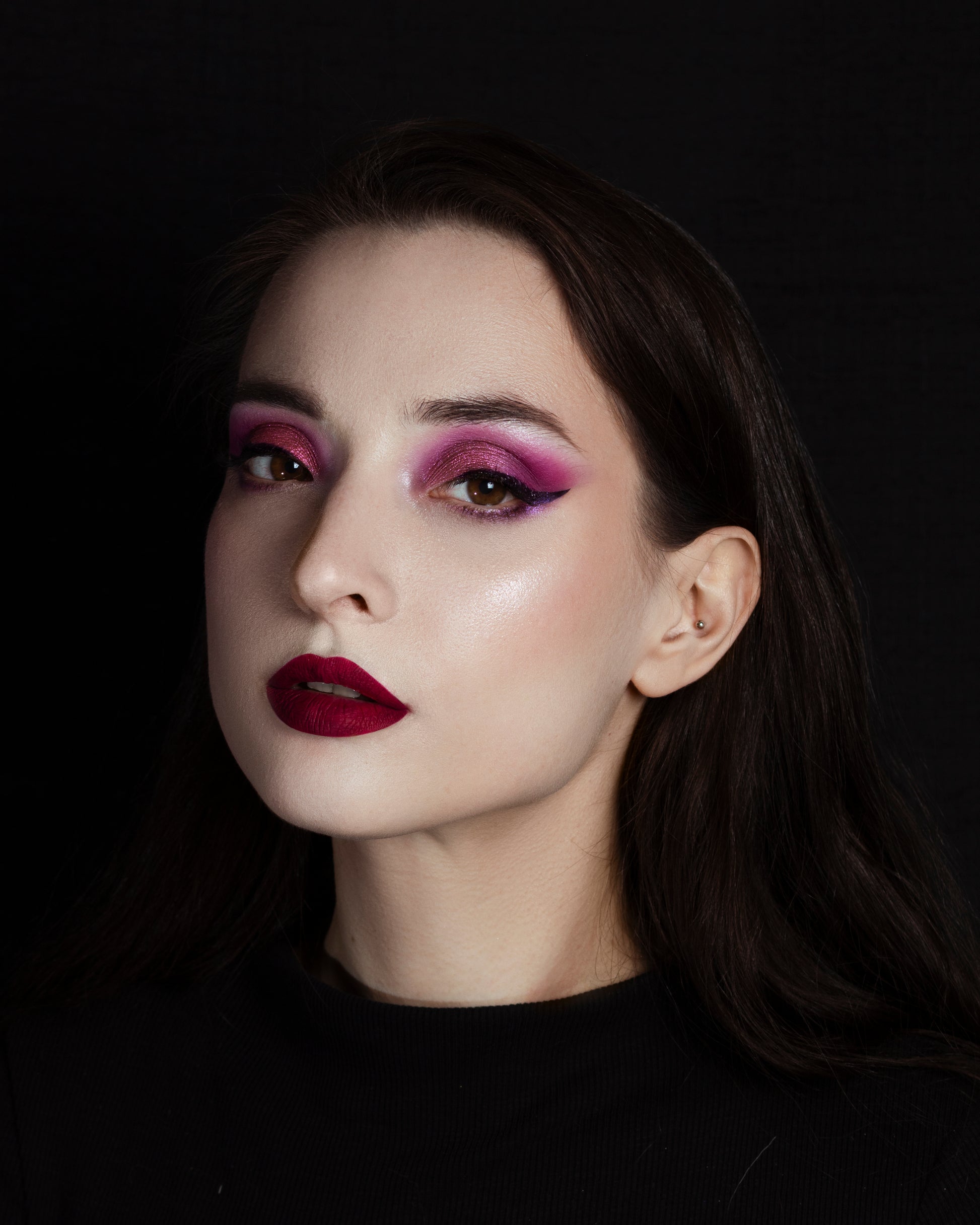 Woman with dark hair and red lipstick against a black background