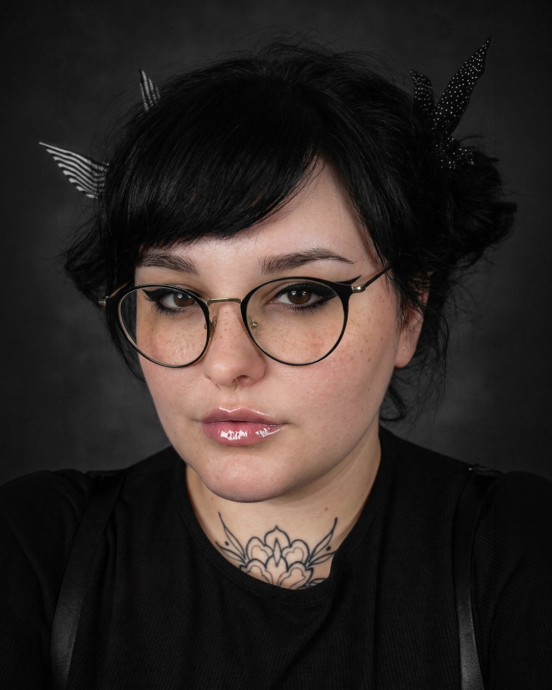 Person with black hair and glasses against a dark background