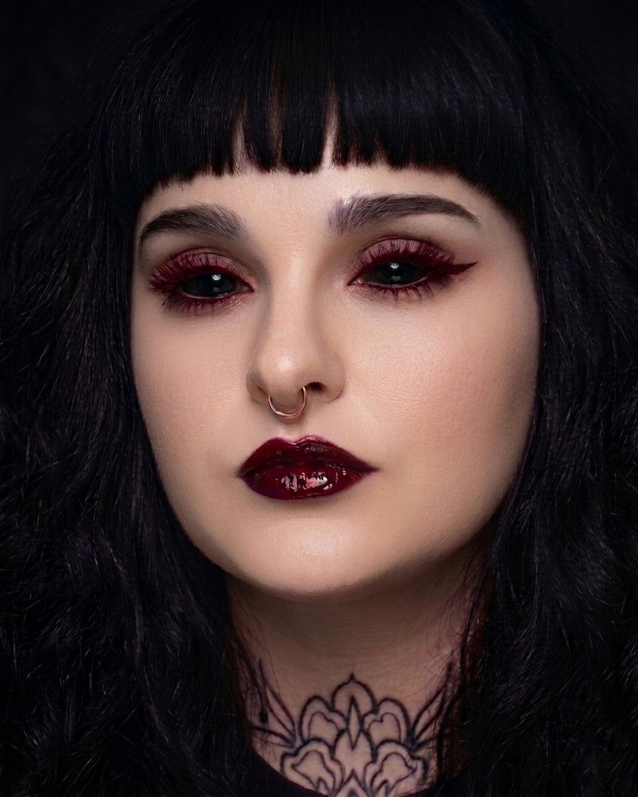 Close-up of a person with dark hair and red lipstick against a black background