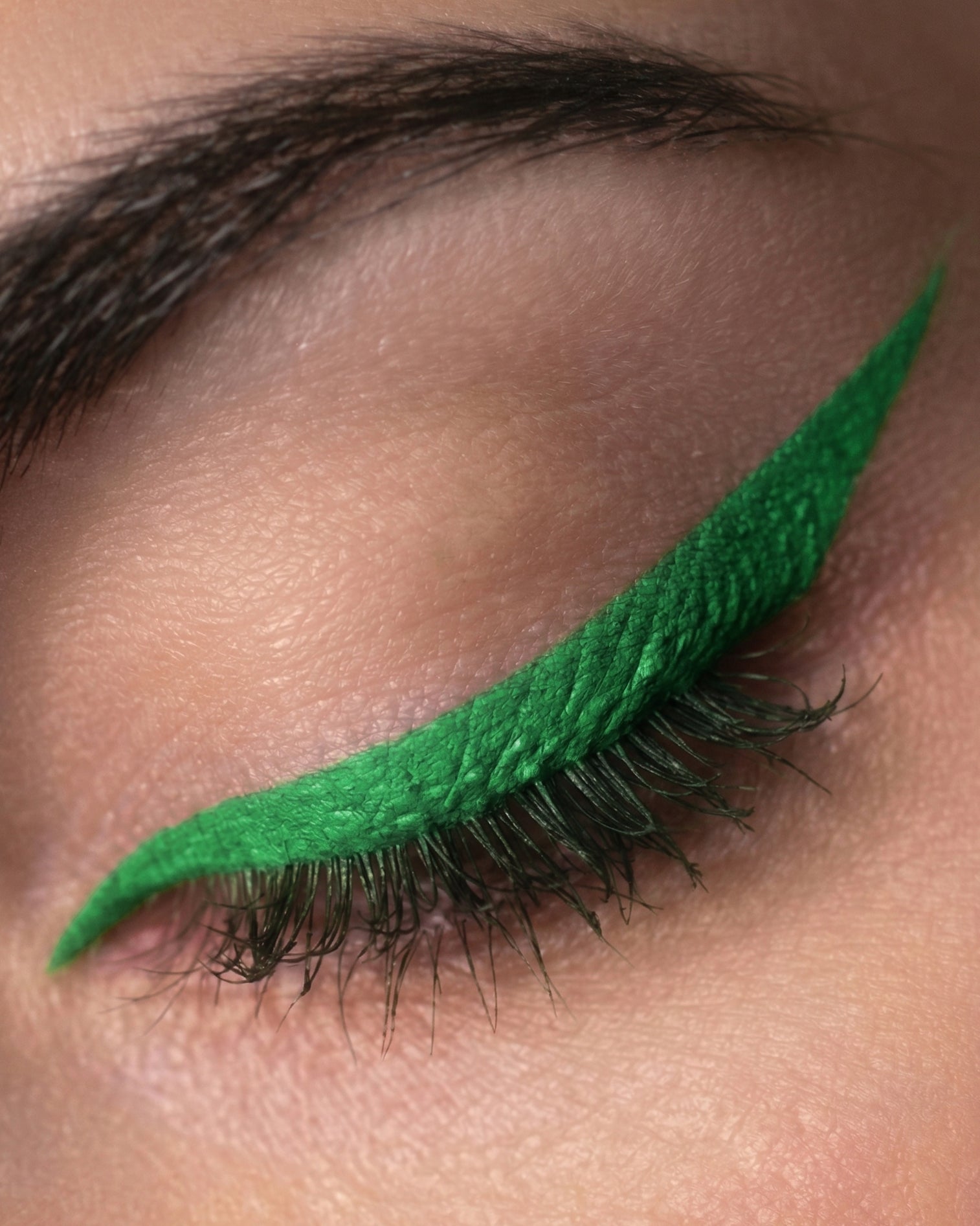 Close-up of an eye with green eyeliner on a neutral background