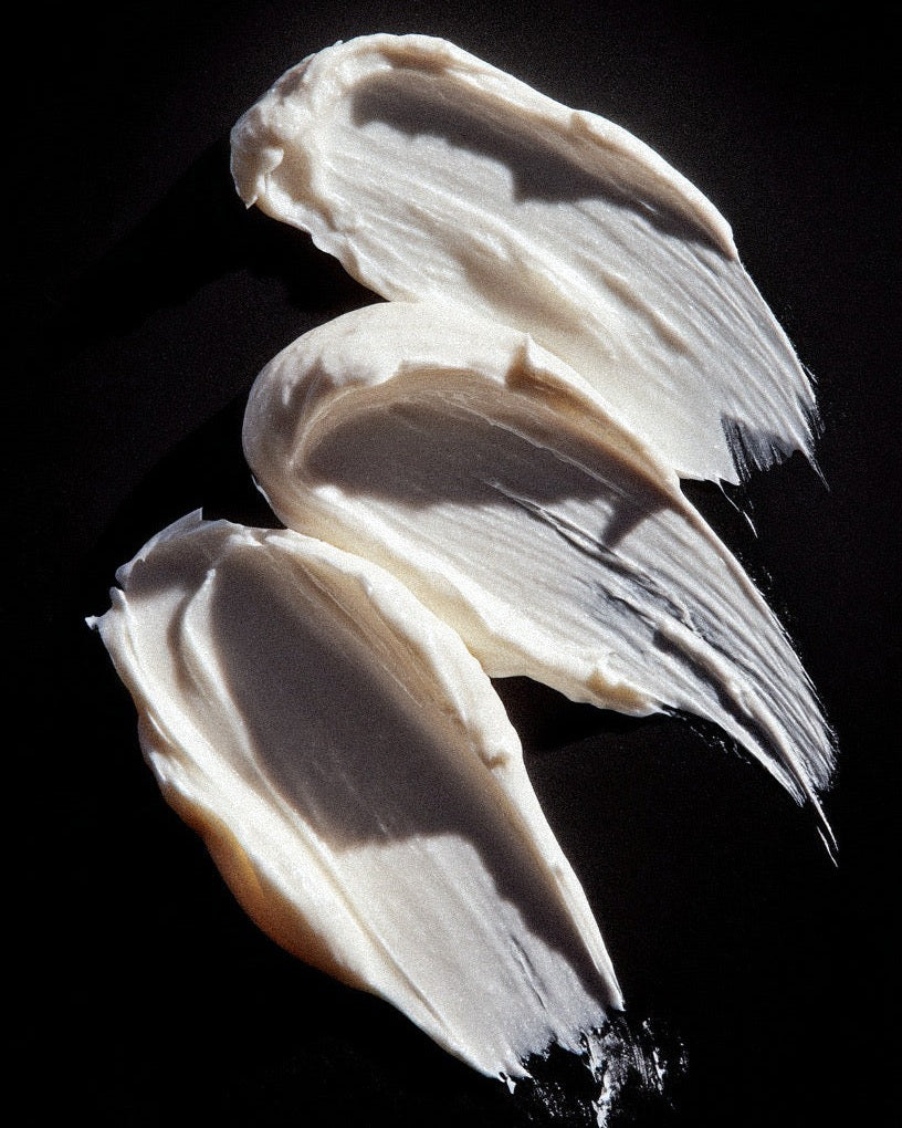 Three swatches of white cream on a black background