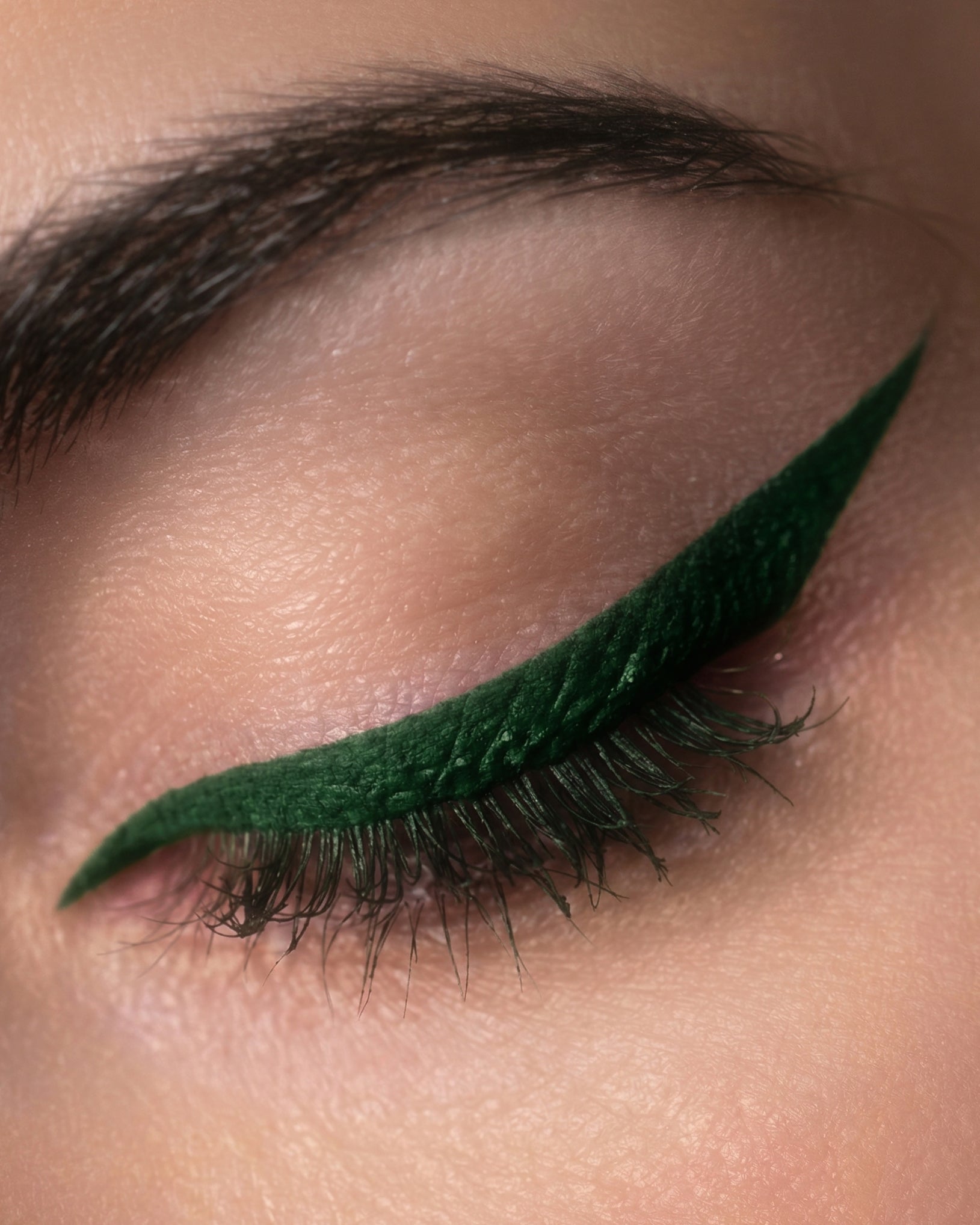 Close-up of an eye with green eyeliner on a neutral background