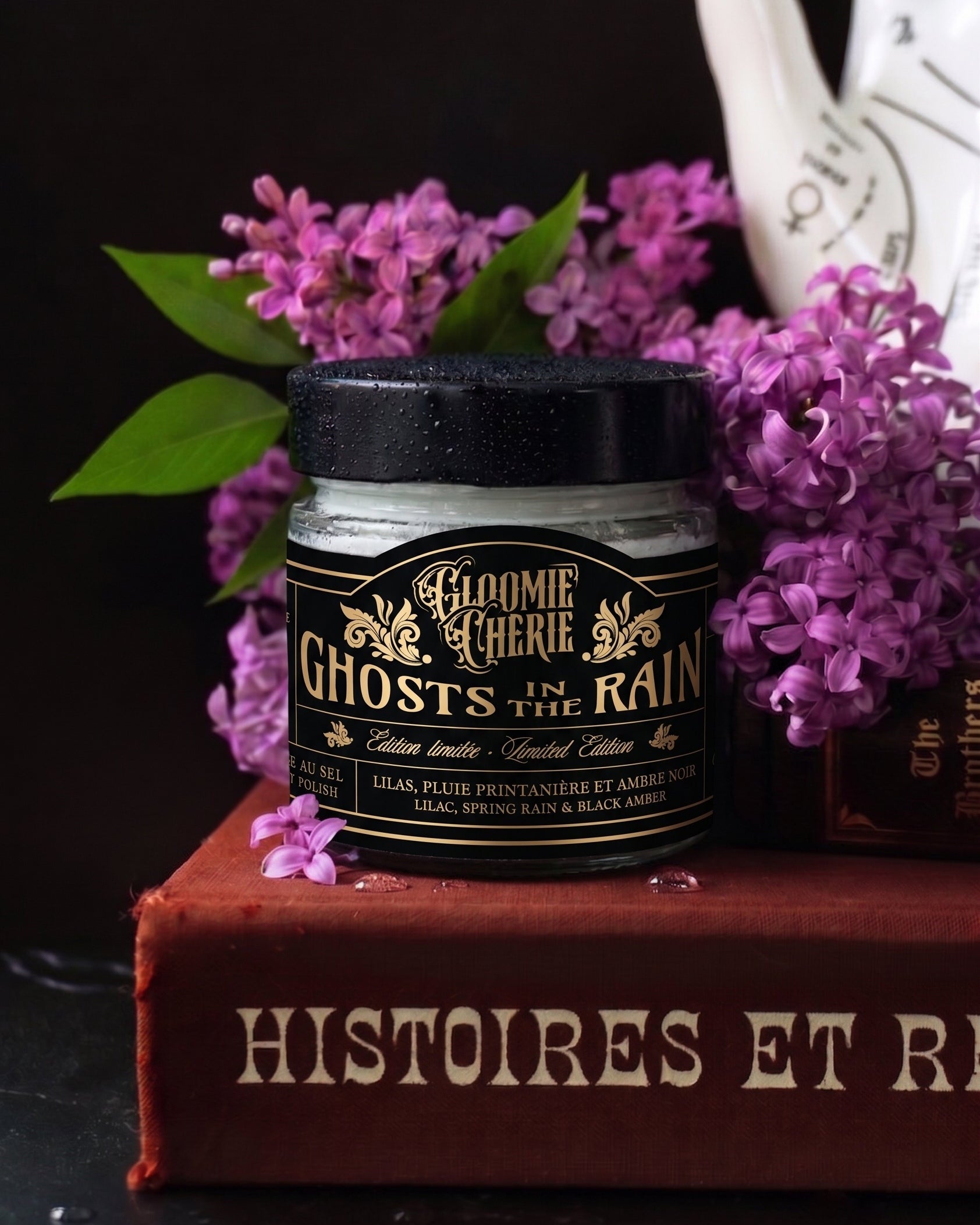 Jar of 'Gloomy Chérie Ghosts in the Rain' body polish on a book with purple flowers