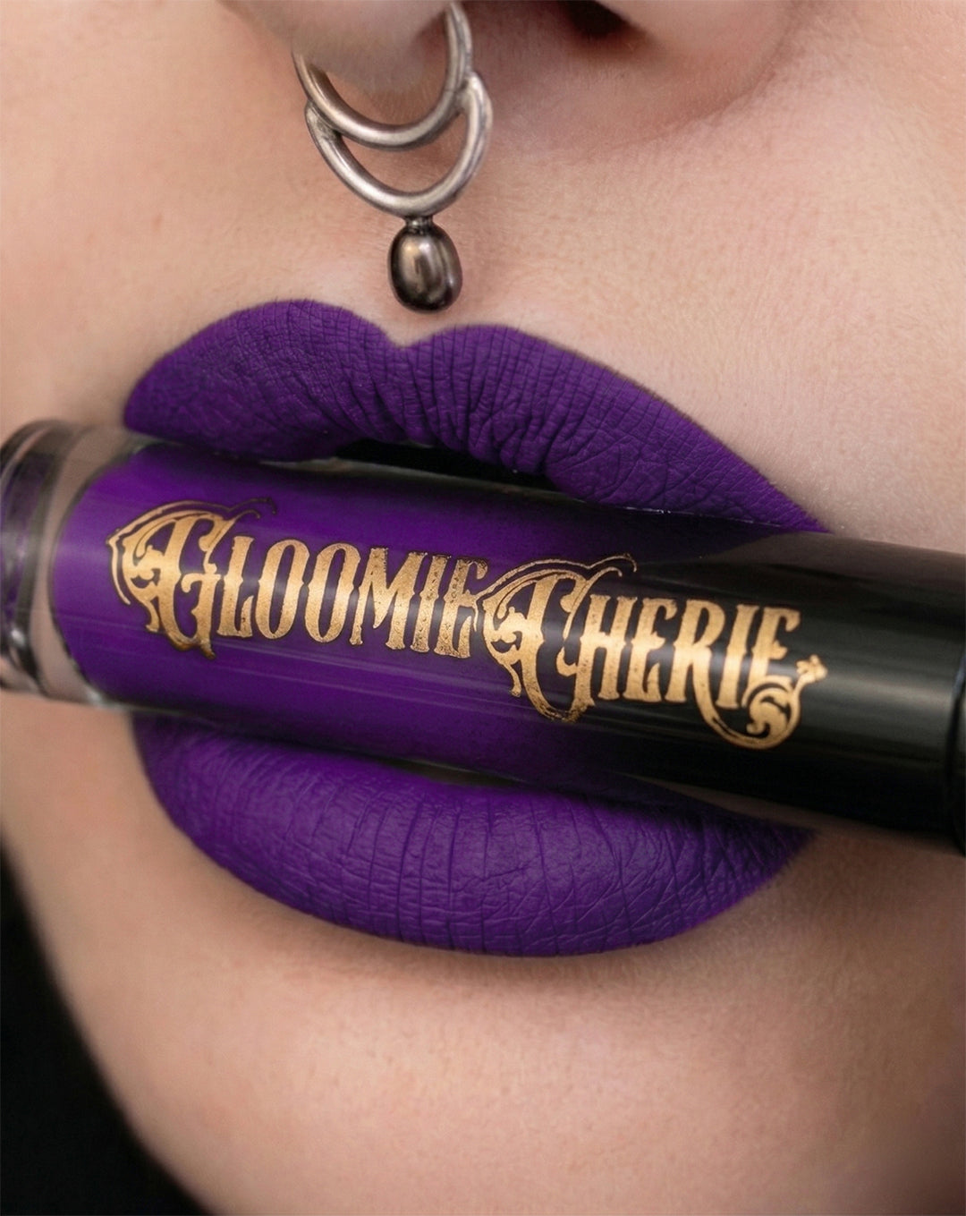 Purple lipstick with 'Gloomie Cherie' branding applied to lips.