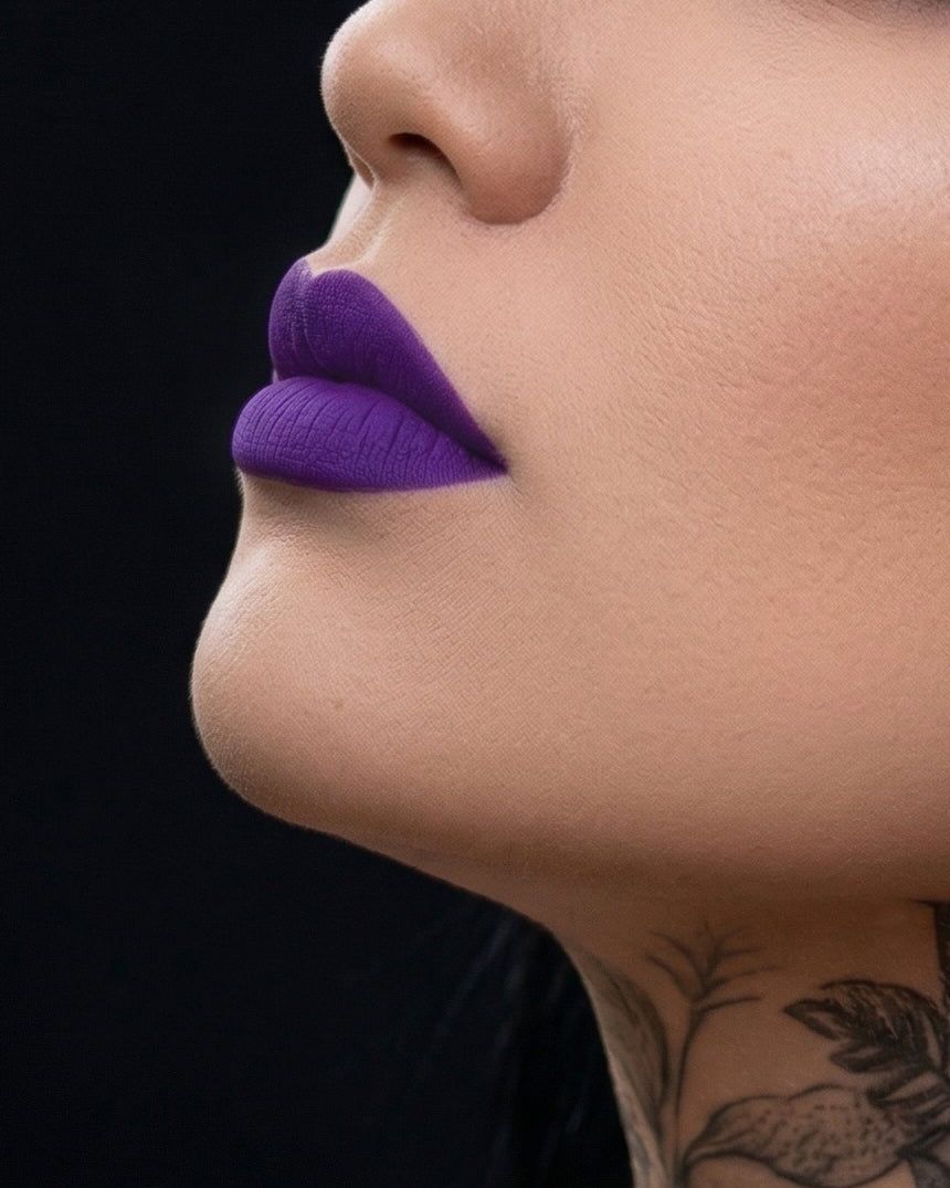 Close-up of a woman with purple lipstick and tattoos on her neck against a black background