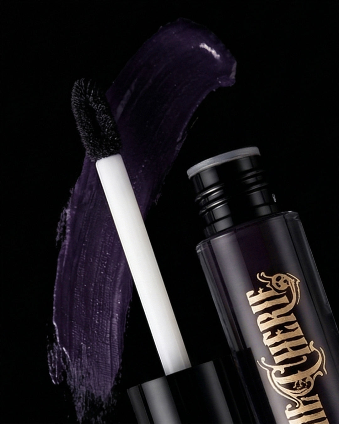 Dark purple lip gloss with applicator and visible brand name on a black background